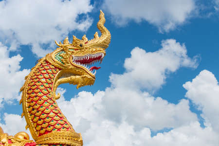 The golden great naga statue with white cloud and blue sky backgroud at Wat Phra Thart Doi Wao, Chiengrai, Thailandの写真素材