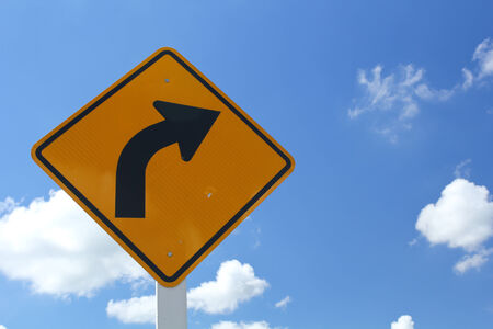 Curved road traffic sign  with white cloud and blue skyの写真素材