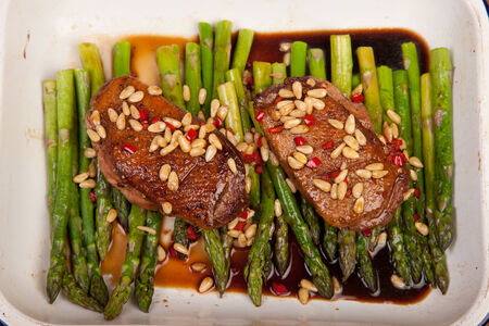 duck breast with pine nuts and asparagus in baking trayの写真素材