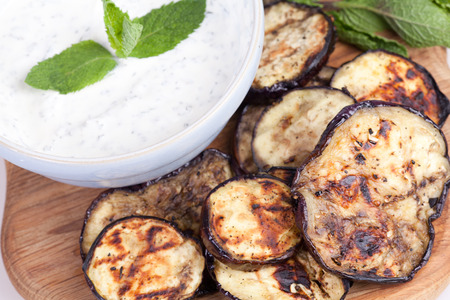 grilled aubergine with mint sauce on chopping board.の写真素材