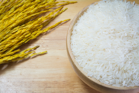Rice in wooden bowl on Sack or wood table backgroundの写真素材