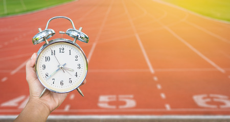 hand holding clock with blur  running track background in 
healthy Conceptの写真素材