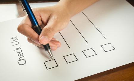 close- up hand holding pen on check list paper with tablet in vintage style