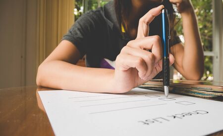 Working woman holding pen on check list paper and keeping hand on chinIn the stressful feelings.の写真素材
