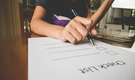 Working woman  hand holding pen on check list paper with tablet in vintage styleの写真素材