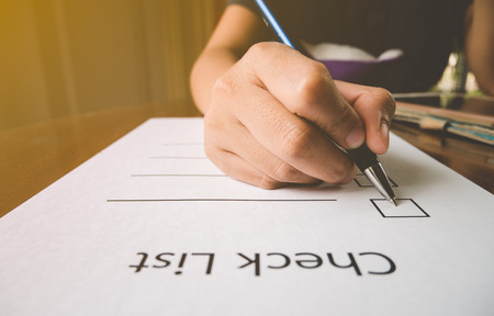 close- up hand holding pen on check list paper with tablet in vintage styleの写真素材