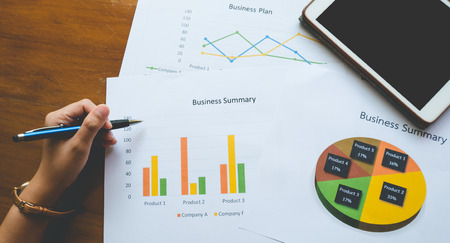 Top - view of  hand holding pen with Business summary or Business plan report with Charts and graphs in Business concept, vintage styleの写真素材