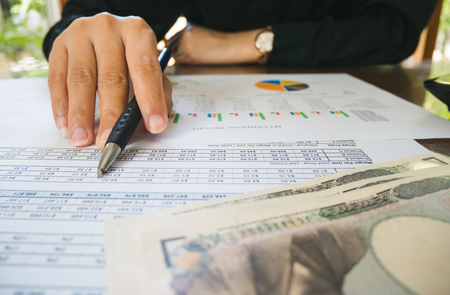Business woman hand hold pen and on Statement or financial report and japan money in business concept.の写真素材