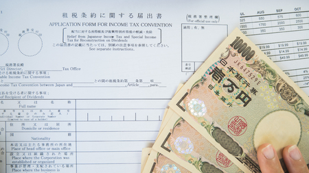 Woman hand hold pen fill in the details on the tax forms paper with yen moneyin business concept.の写真素材
