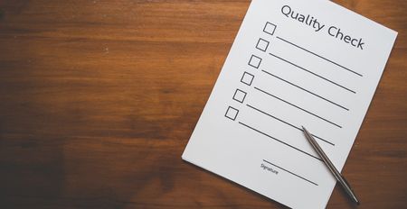 Flat lay and  Top view of quality Check list paper with pen on wooden table in business concept,vintage styleの写真素材