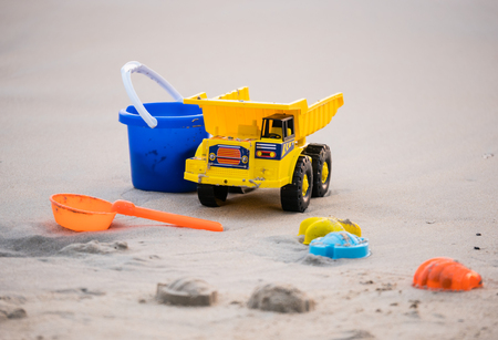 Beach toys series. The yellow truck, blue tank and scoop device. On the beach in holiday conceptの写真素材