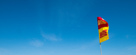 A word Swin Here on the red and yellow flags on the beach with blue sky .To tell the point safe for swimming In security conceptの写真素材