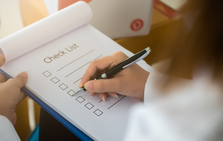 Close- up hand holding pen on check list paper and the format for filling in information in business concept,vintage style and softtoneの写真素材