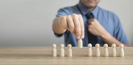Owner is picking or select wood figure on the wooden roe in human resource management concepts Teamwork.Success Leadership,Business Progress and Competition on wood table and copy spaceの写真素材