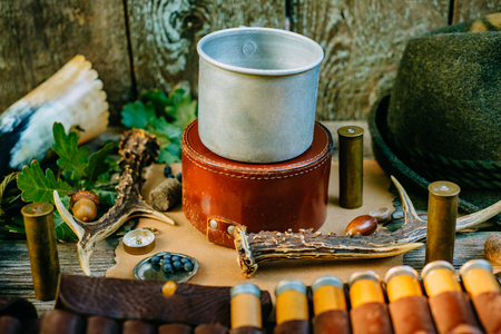 Closeup aluminum mug for information, stand on round hunt box among hunting or tourist vintage...
