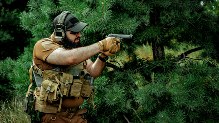 Airsoft middle eastern beard man aiming at the gun. Forest backgroundの写真素材