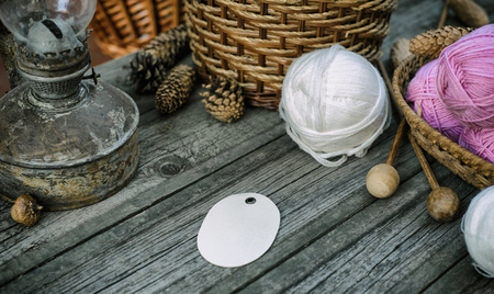 Oval label on basket and ball on desk. Close up two pink balls of wool threads on vintage wood deskの写真素材