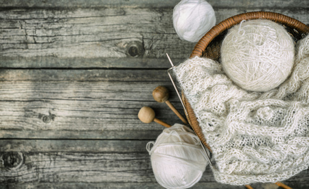White wool threads roll to basket with knitting and knitting needles on vintage woodの写真素材