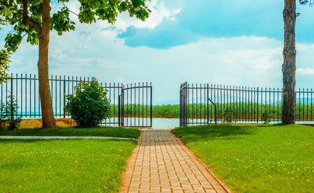North macedonia. Ohrid. Path through green lawn to gate and lake in sunny day.の写真素材