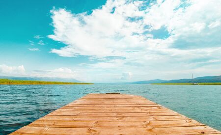 North macedonia. Ohrid. Wood pier in Ohrid lake in sunny day with reeds, pier and mountaines on...