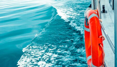 Red lifebuoy on ship railing with sea surface.の写真素材