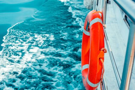 Red lifebuoy on ship railing with sea surface.の写真素材