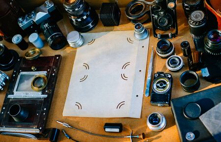 Retro photographical mockup. Closeup photoalbum sheet in center and vintage photographic accessories and quipments around on Wooden Background. Top viewの写真素材