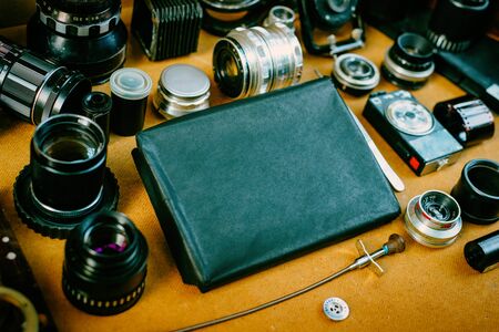 Retro mockup, retro black pack for photo paper in center and vintage photographic accessories and quipments around on Wooden Background.の写真素材