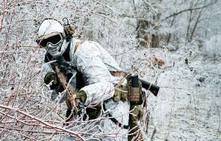 Military man in white camouflage uniform with machinegun. Soldier sneaking in the winter forest with machinegun. Front view.の写真素材