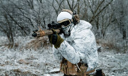 Closeup military man in white camouflage uniform with machinegun. Soldier aims of the machinegun.の写真素材