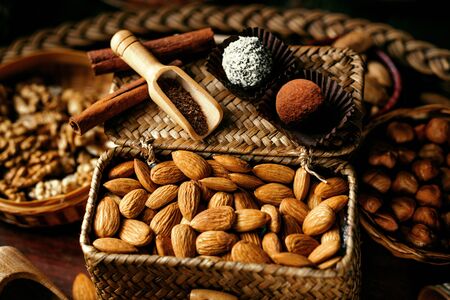 Handmade truffles inside of candy wrapper stand on wicker basket with almonds.の写真素材
