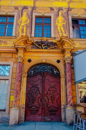 Wroclaw, Poland - 2012: Yellow stucco arc with beautifully decorated red wooden door with curve decorの写真素材