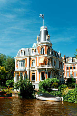 Canal in Amsterdam with boats and beautiful historic houseの写真素材