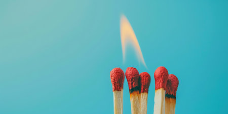 Matchstick burning on blue background with copy space. Close up.の素材