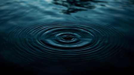 Water drop with ripples on dark blue water surface. Abstract background.の素材