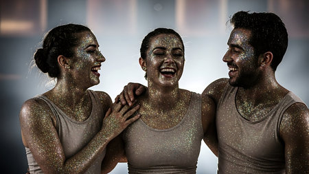 Group of people with glitter on their bodies against room with white wallの素材
