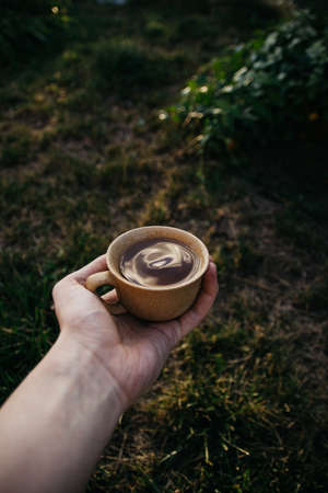 mug of coffee, tea on the background of home garden and sunsetの写真素材
