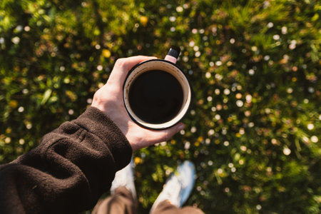 cropped image of man holding cup of coffee on grassy field