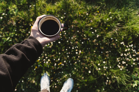 A cup of coffee in the hands of a girl in nature.
