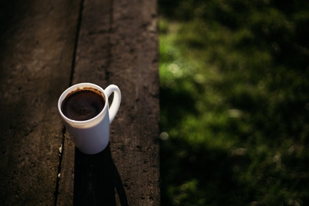 Cup of coffee on the wooden table in the garden. Selective focus.