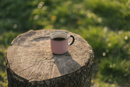 Cup of coffee on a stump in the garden, shallow depth of fieldの写真素材