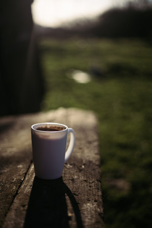 Coffee cup on a wooden table in the garden. Selective focus.