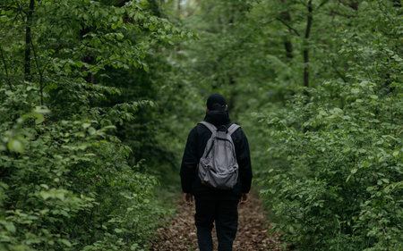 A man with a backpack on his back walks through the forest.