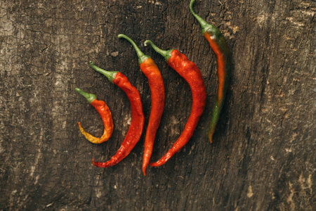 Hot chili peppers on old wooden background, top view, copy space