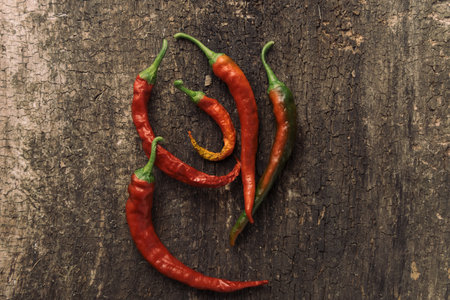 Hot chili peppers on old wooden background, top view, copy space