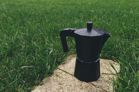 Black coffee maker on green grass background, close-up, selective focusの写真素材