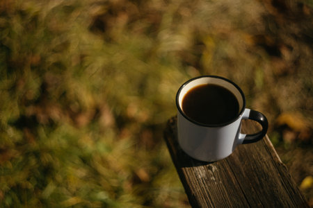Cup of coffee on a wooden bench in the park. Selective focus.の写真素材