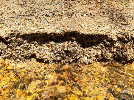 A closeup shot of a rock covered with sand under the water