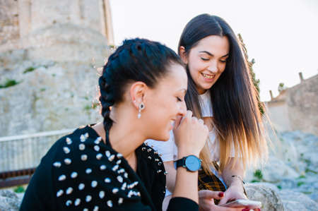 couple of girls playing with the cell phone in the streetの写真素材