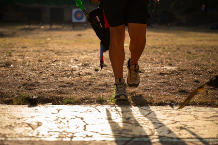 A man is walking on a dirt field with a bow and arrow in his hand. Concept of adventure and outdoor...